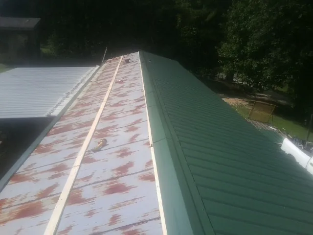 Old rusted panels beside newly installed green metal roofing — Wind Damage Roof Repair by Roofing Brothers in Biddeford Pool