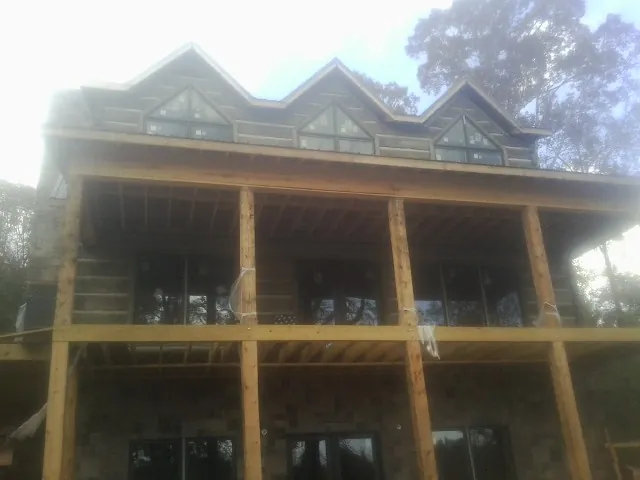 Dormers and porch framing on a large log home under construction — Roof Coating work by our crew in Biddeford Pool
