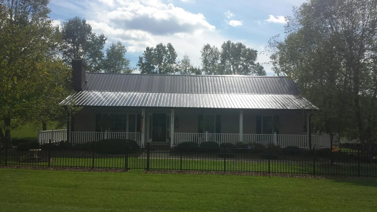 Gray metal roof on a brick ranch with a full width front porch — Gutter Guard Installation work by our crew in Biddeford Pool
