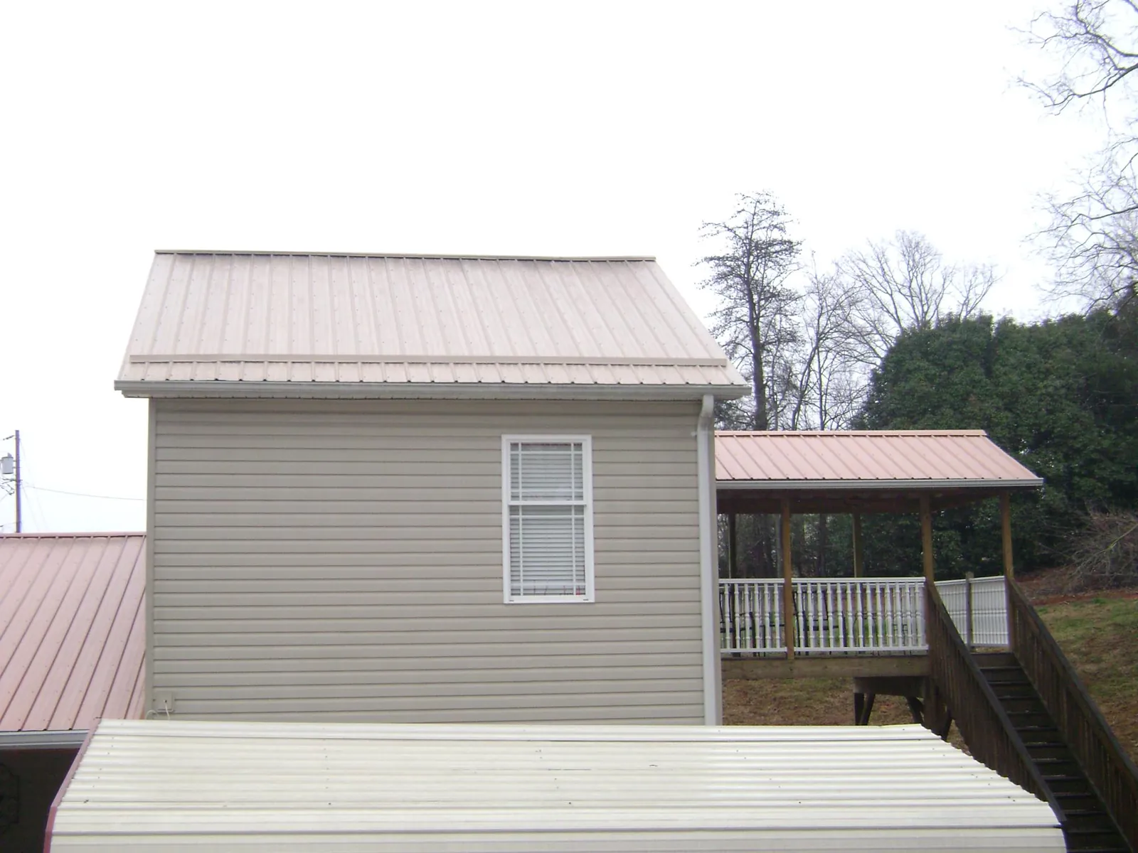 Tan metal roofs on a two story addition and attached porch, from a Roof Replacement job in Biddeford Pool