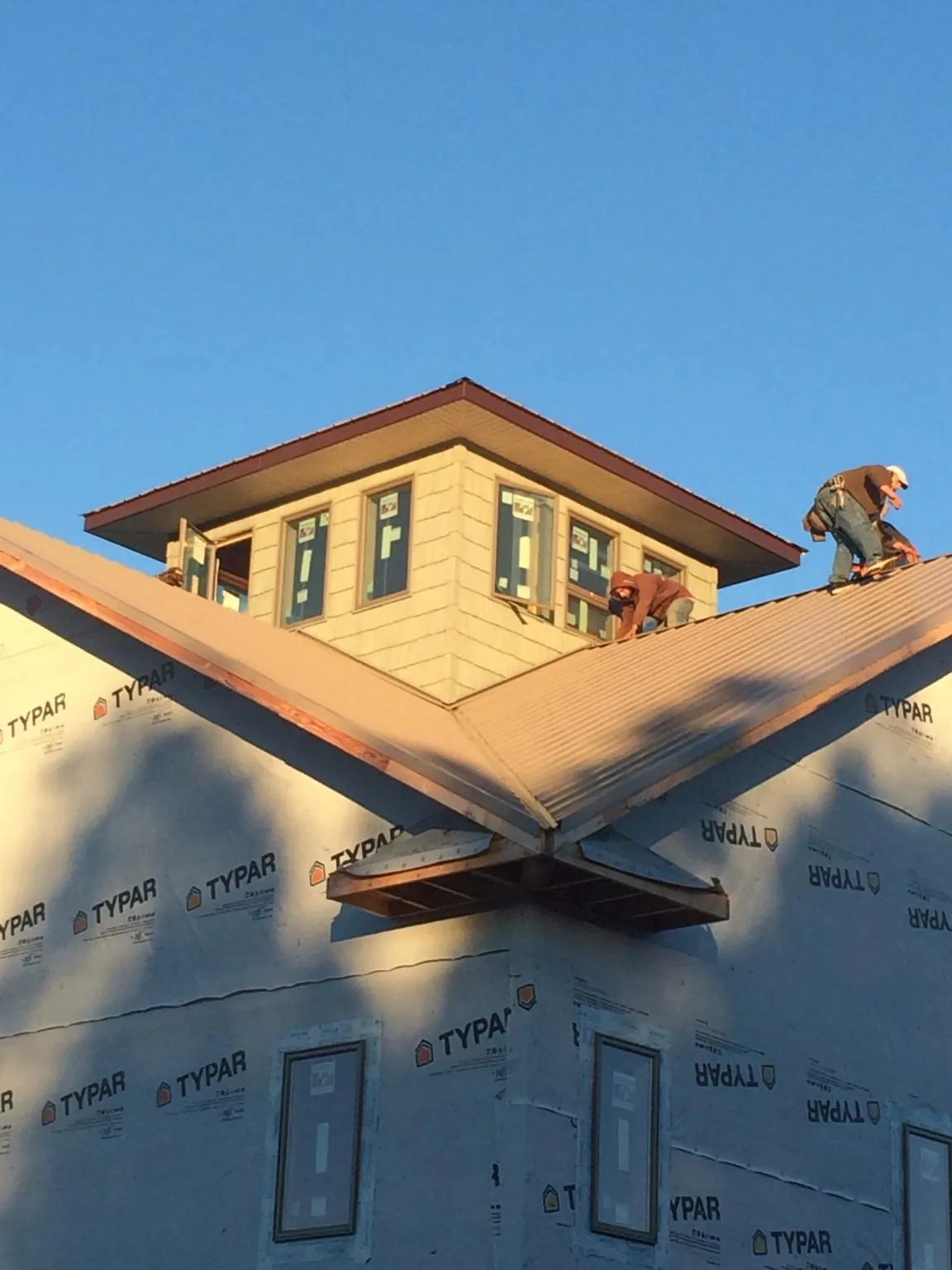 Roofers working around a rooftop cupola on a new metal roof at sunset — Roof Waterproofing in Biddeford Pool by Roofing Brothers